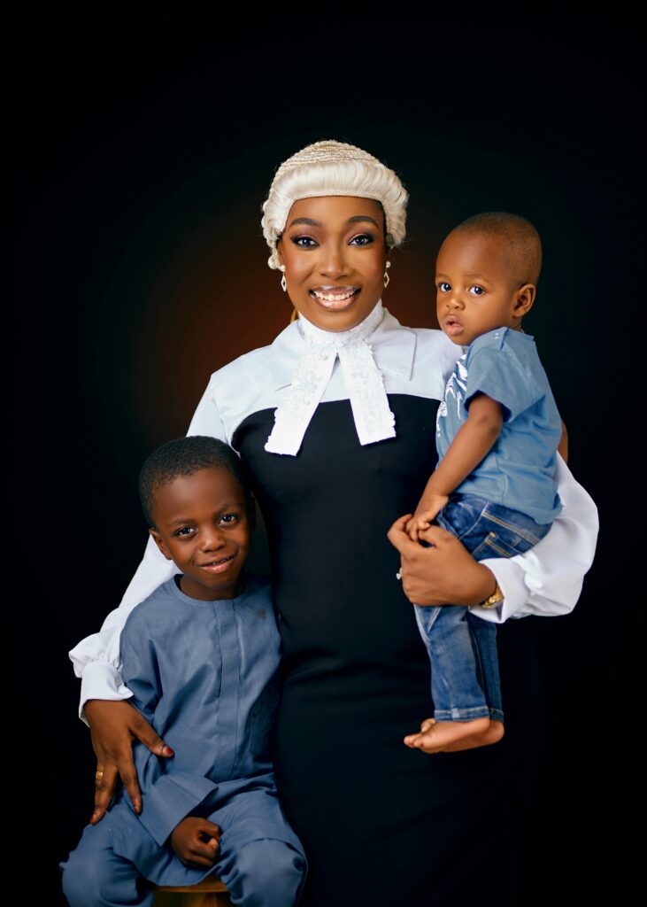 A smiling lawyer in formal attire poses with two boys in a studio portrait.