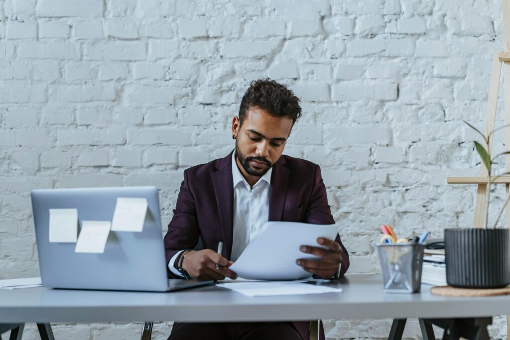 A professional man reviews documents in a modern office setting, focused on his work.