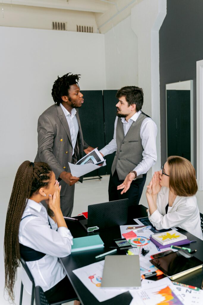 Colleagues engaged in a lively discussion around a workspace table, focusing on conflict resolution.
